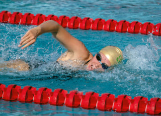 a boy swimming in a pool wearing a swimming cap