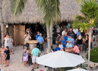 a crowd of people standing around tables and umbrellas