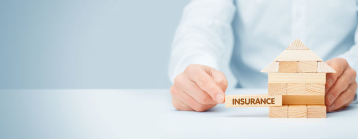a person holding a wooden block with the word insurance on it