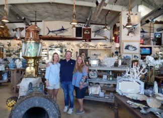 a group of people standing in a room filled with antiques