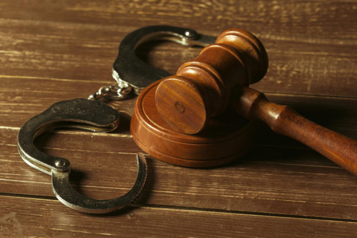 a wooden gaven and handcuffs on a wooden table