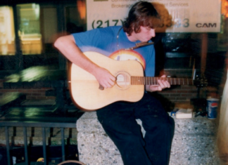 a man sitting on a ledge playing a guitar