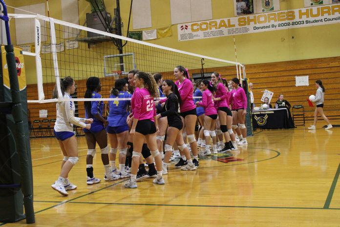 a group of girls in pink shirts playing volleyball