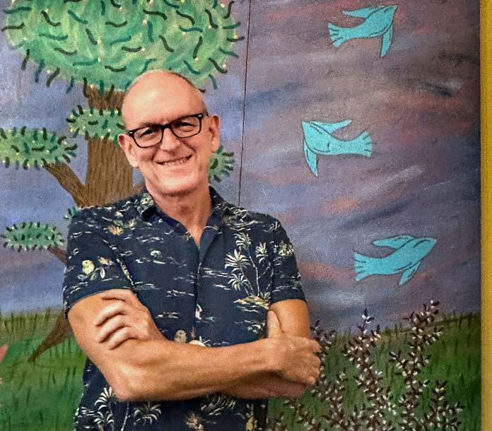 a man standing in front of a painting of a tree