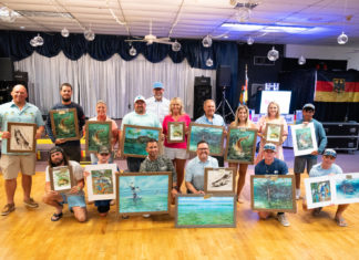 a group of people holding up paintings on a wooden floor