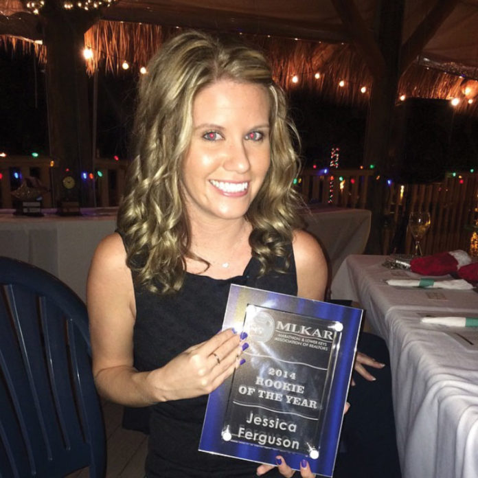 a woman holding up a plaque in front of a table