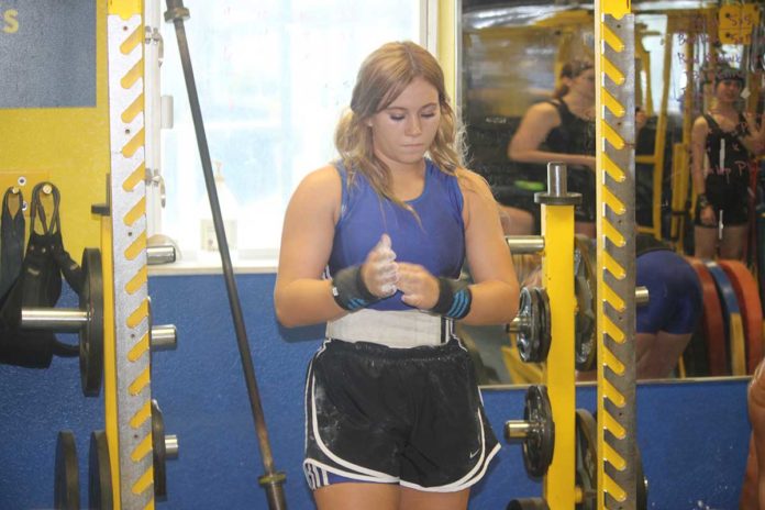 3 a woman standing in a gym holding a cell phone