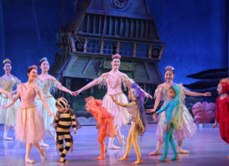 a group of ballerinas on stage with their hands in the air