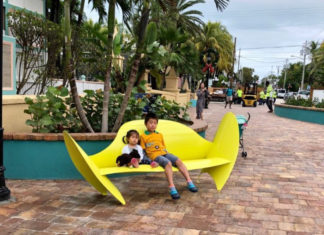 a couple of kids sitting on top of a yellow bench