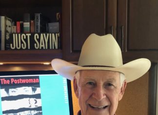 a man wearing a cowboy hat sitting in front of a computer