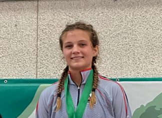 a girl with braids and a medal standing in front of a wall