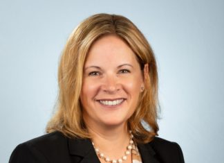 a woman wearing a suit and pearls smiling