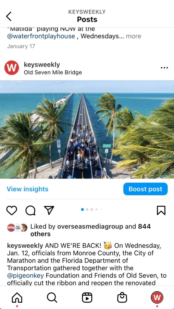 a group of people walking down a road next to the ocean