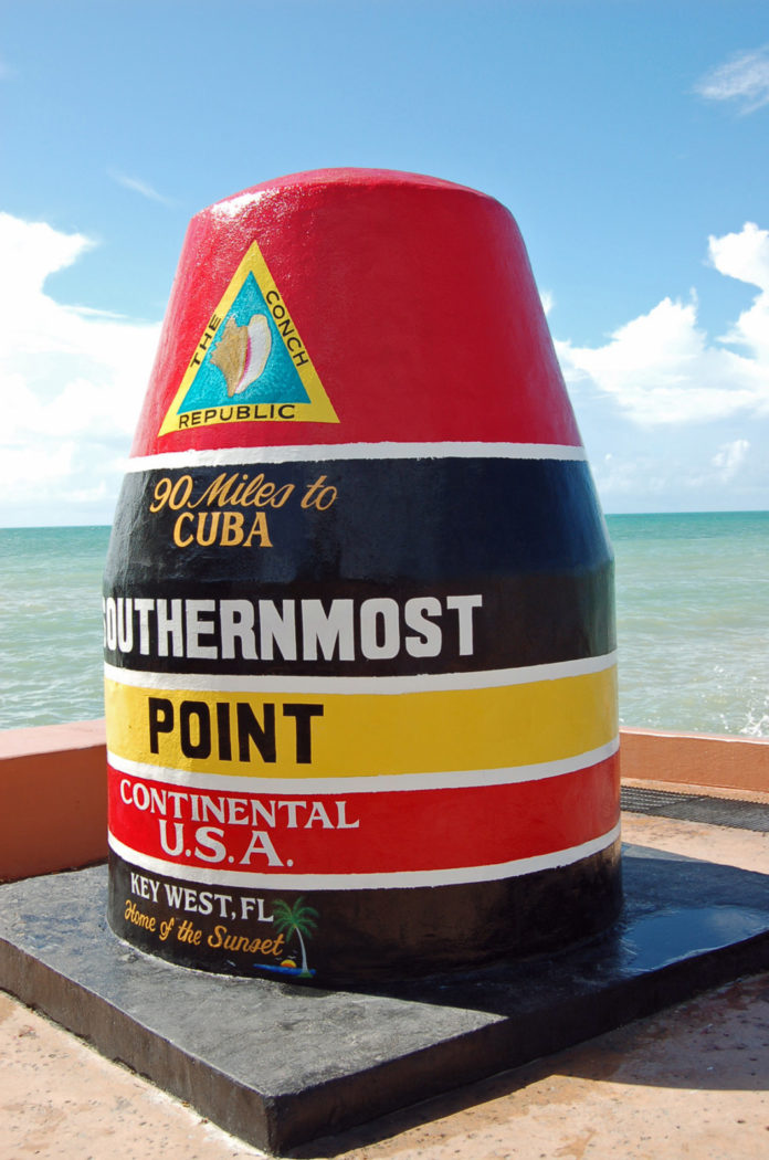a red, yellow, and black pole on a beach next to the ocean