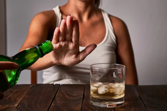 a woman sitting at a table with a glass of alcohol