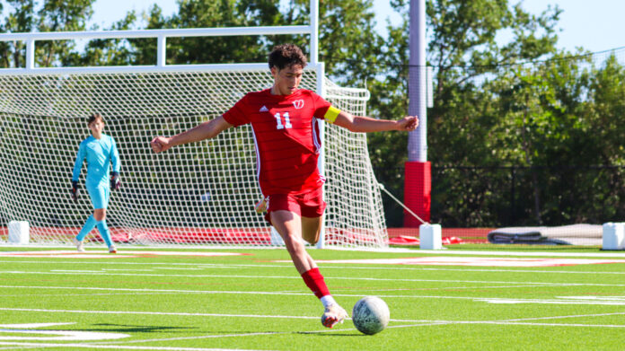 a young man kicking a soccer ball across a field