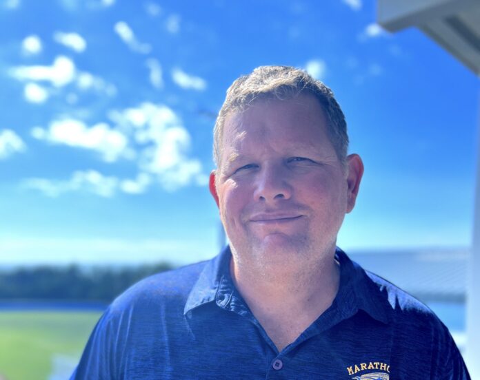 a man in a blue shirt standing on a porch