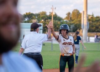 DOLPHINS & HURRICANES SOFTBALL TRADE RUNS IN CLOSE KEYS MATCHUP a group of people on a field playing baseball