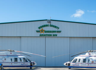 two helicopter parked in front of a hangar