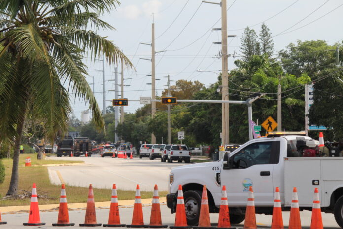 a white truck driving down a street next to traffic cones