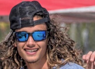 a man with long curly hair wearing a hat and sunglasses