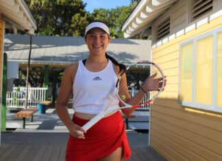 a woman standing on a porch holding a tennis racquet