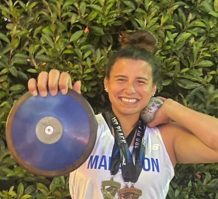 a woman holding a blue frisbee in front of a bush