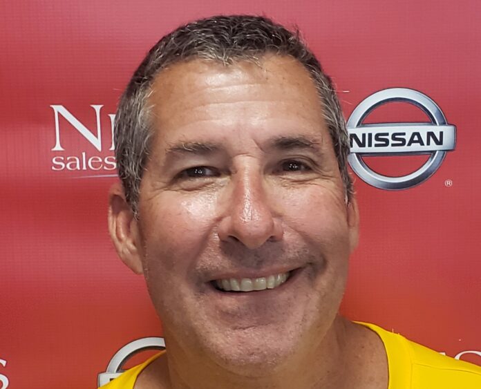 a man in a yellow shirt smiling at the camera