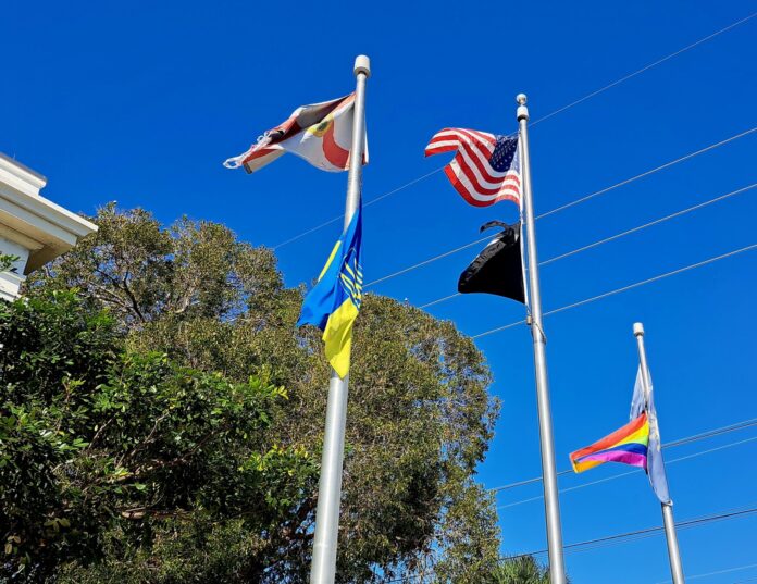 a group of flags flying in the air next to a building