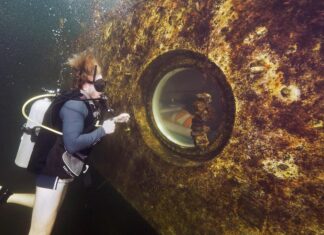 a man in a scuba suit is standing in front of a large object