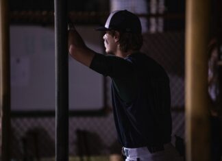 a baseball player leaning on a pole at night