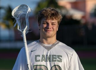 a young man holding a lacrosse stick on a field