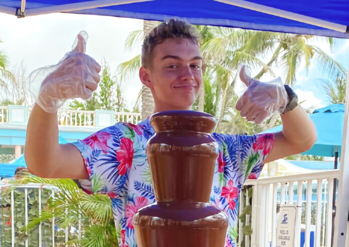 a man standing next to a chocolate fountain