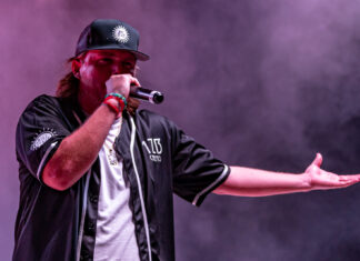GARRETT HUGHES BENEFIT CONCERT BRINGS COMMUNITY TOGETHER a man with long hair and a baseball cap holding a microphone