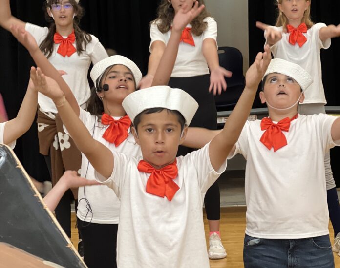 a group of children in white shirts and red bow ties