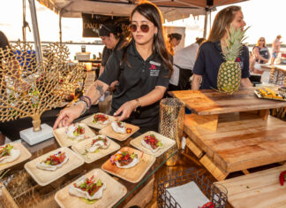 a group of people standing around a table with food on it