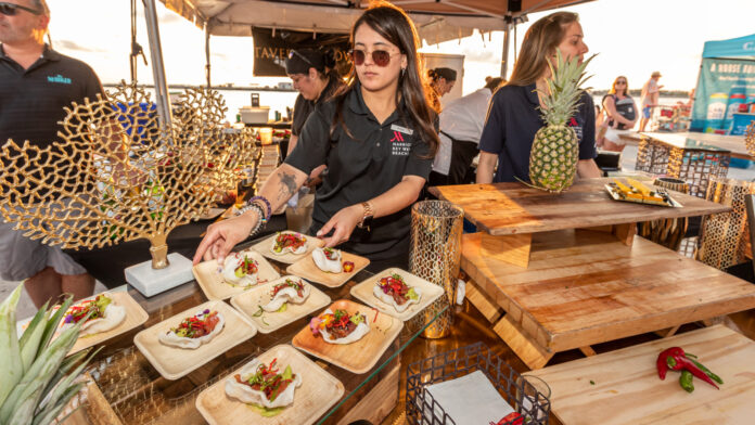 a group of people standing around a table with food on it