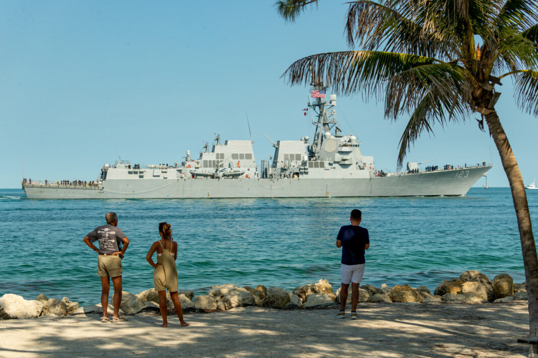 a group of people standing on a beach next to a large ship