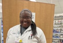 a woman in a white lab coat smiles at the camera