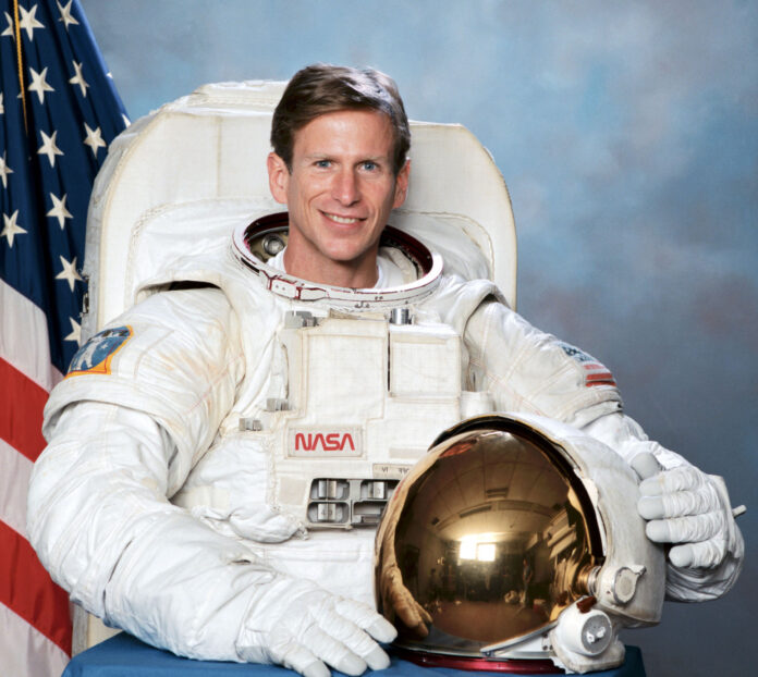 a man in an astronaut suit holding a golden helmet