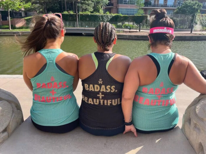 three women sitting on a wall looking at a body of water