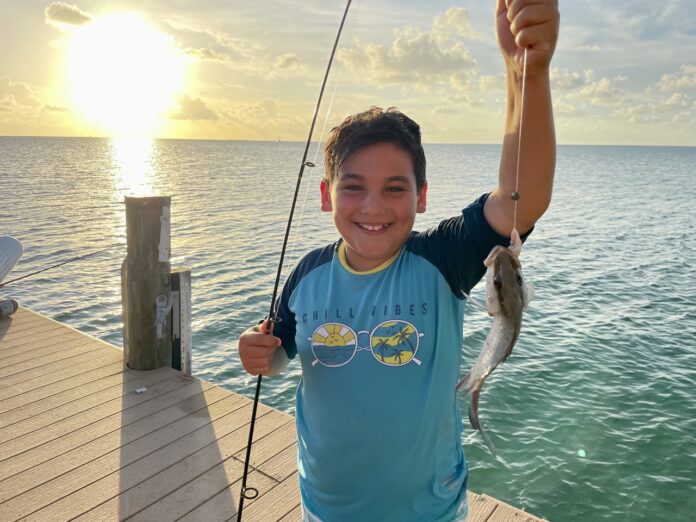 a young boy holding a fish on a dock