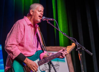 a man in a pink shirt playing a guitar