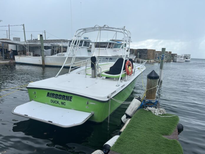 a green and white boat docked at a dock