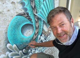 a man sitting in front of a painting of a peacock