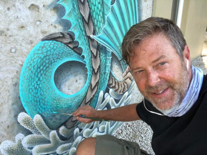 a man sitting in front of a painting of a peacock