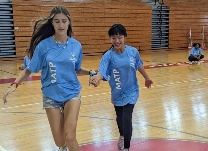 a couple of women running across a basketball court