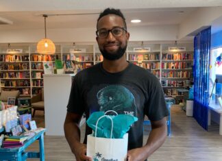 a man standing in a library holding a bag
