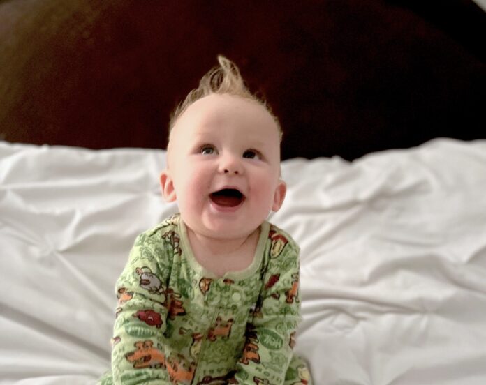 a baby sitting on top of a bed wearing pajamas