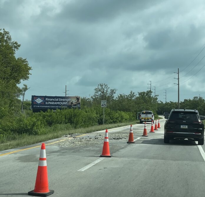 a black truck driving down a road next to traffic cones